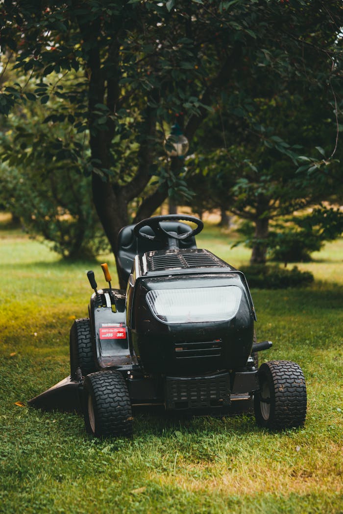about-02 A riding lawn mower in a verdant backyard surrounded by trees, perfect for yard maintenance.